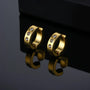 Gold zirconia bold clip on hoop earrings with crystal details, front view on reflective surface