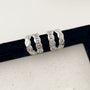 Braided baguette clip-on earrings in white gold, displayed on black velvet holder, angled front view