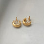 Brushed gold clip-on hoop earrings displayed on white fabric, showing polished curved design from front angle