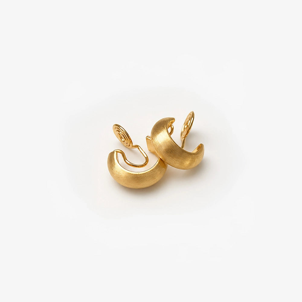 Brushed gold clip-on hoop earrings displayed, showing polished curved design from front angle