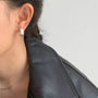 Brushed silver clip-on hoop earrings worn on ear, side view against white background