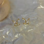 Gold butterfly zirconia invisible clip-on earrings front view displayed on white pearl fabric background