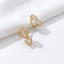 Gold butterfly wing clip-on pearl earrings displayed on white marble surface showing filigree detail and lustrous pearls