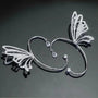 Butterfly wing ear cuff in white gold with diamond details, displayed on gray background showing front angle view