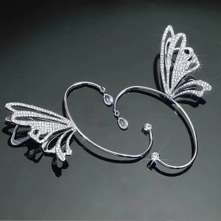 Butterfly wing ear cuff in white gold with diamond details, displayed on gray background showing front angle view