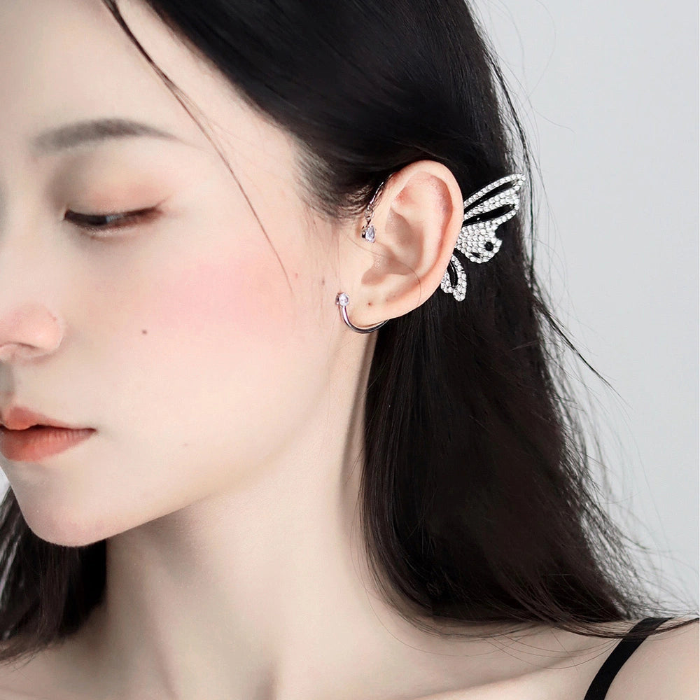 Model showcasing the Butterfly Wing Ear Cuff in White Gold, emphasizing the elegant wrap-around design and secure fit on the ear." "Close-up image of the Butterfly Wing Ear Cuff in White Gold, focusing on the luxurious white gold plating and sophisticated butterfly wing design." "Side angle of the Butterfly Wing Ear Cuff in White Gold, capturing the sparkling zircon stones and graceful curve of the wing design.