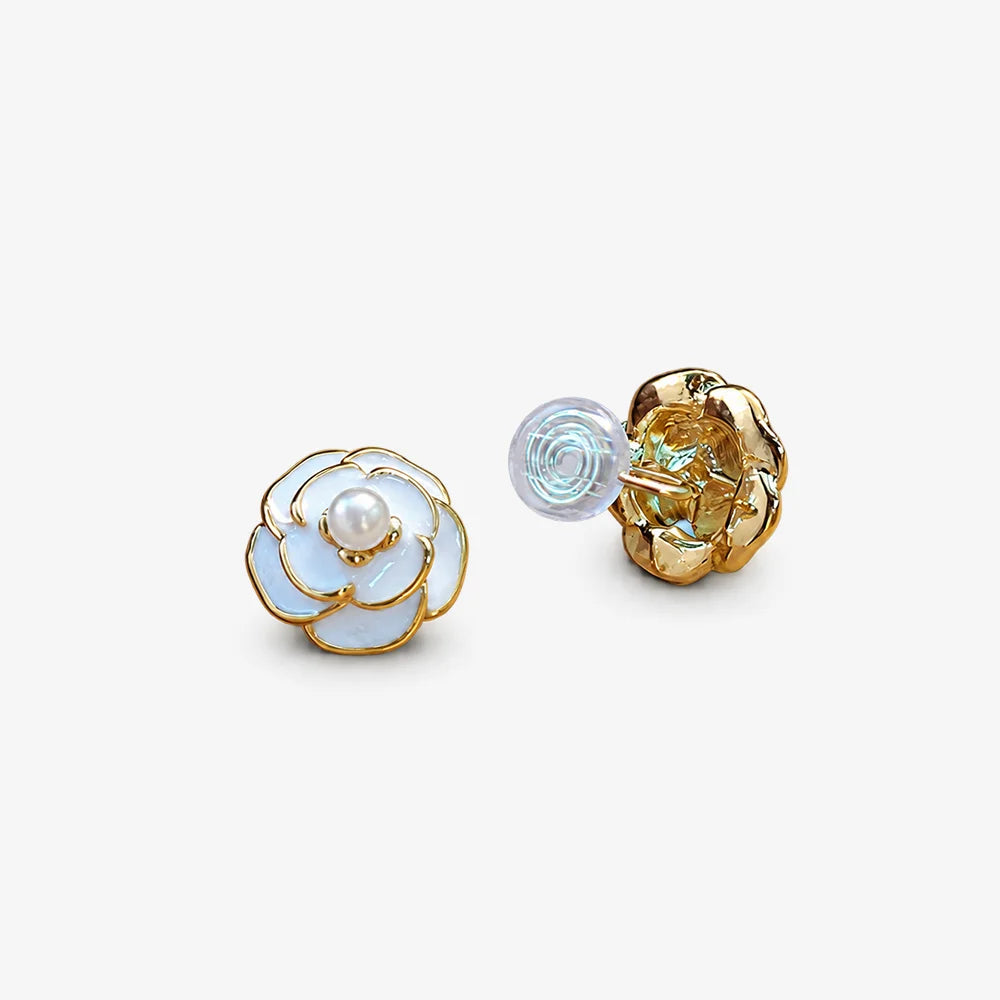 Camellia Enamel Clip On Earrings in white and gold, displayed on white surface showing detailed flower design and pearl center