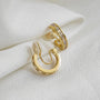 Gold channel-set zirconia clip-on hoop earrings displayed on white fabric background showing polished finish and cubic zirconia detail
