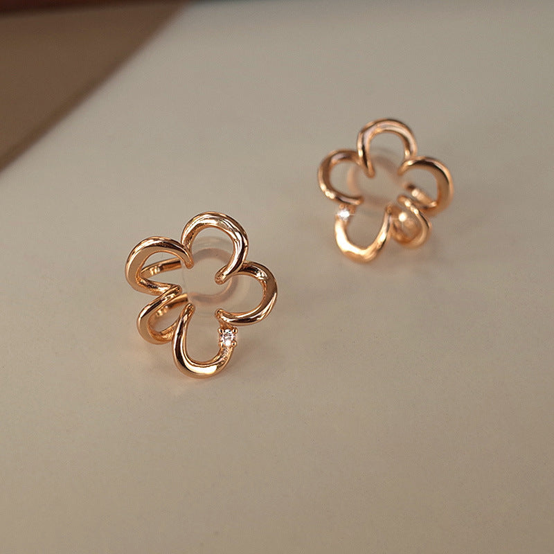 Elegant Cherry Blossom Floral Helix Ear Cuffs in rose gold, resting on a dark traditional container, their Sakura-shaped design highlighted by the intricate craftsmanship and central zircon accent.