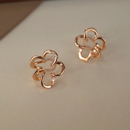 Elegant Cherry Blossom Floral Helix Ear Cuffs in rose gold, resting on a dark traditional container, their Sakura-shaped design highlighted by the intricate craftsmanship and central zircon accent.