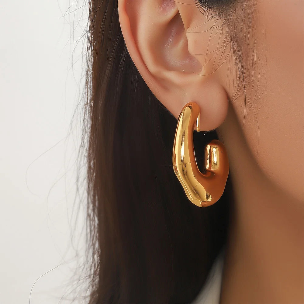 Gold chunky curved hoop clip-on earrings side view worn on ear with long dark hair