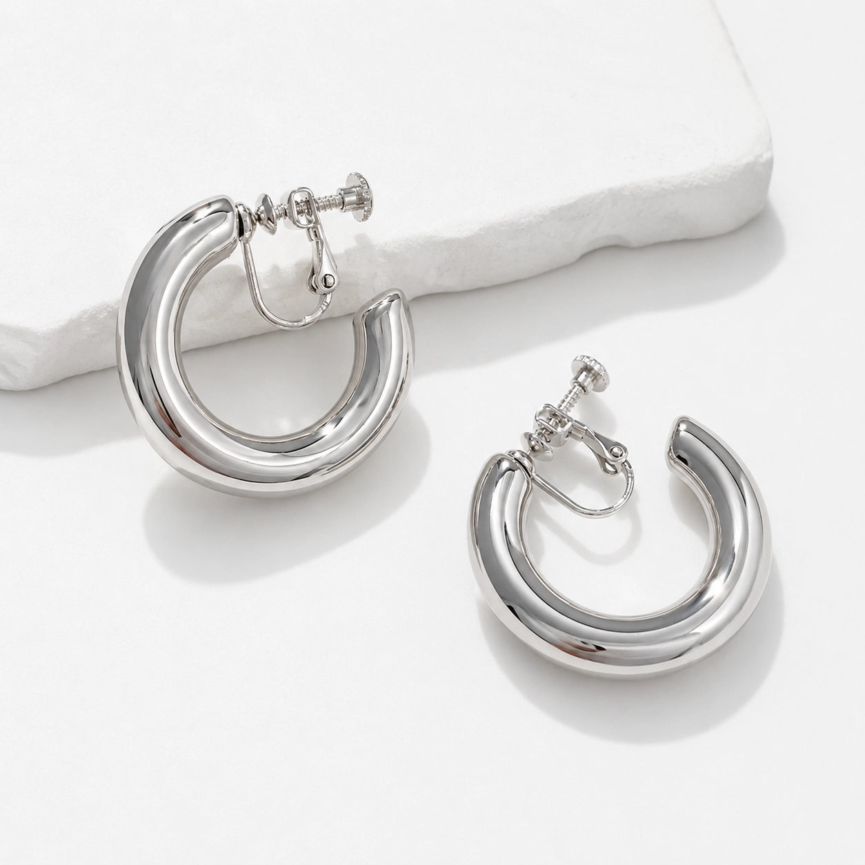 Silver classic hoop clip-on earrings displayed on white background showing polished metal finish and secure closure mechanism