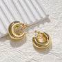 Gold classic bold hoop clip on earrings displayed on white textured background with shadows