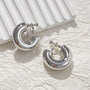 Classic bold silver hoop clip-on earrings displayed on white textured fabric background
