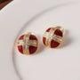 Crimson enamel and gold cross clip-on earrings displayed on white plate, front view showing detailed design