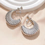 Silver croissant semi hoop clip-on earrings displayed on beige fabric, showing detailed ridged texture and shine from above