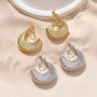 Gold and silver croissant semi hoop clip-on earrings flat lay on beige background with ceramic dish