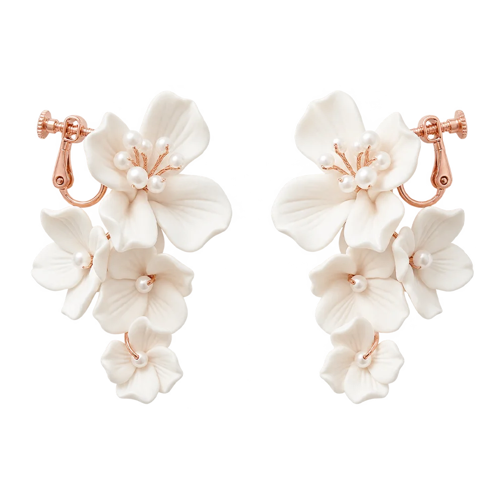 A pair of dangling floral earrings with white flower petals and small pearl-like beads, set in rose gold-tone metal, shown on a plain white background.