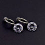 Diamond charm hoop clip-on earrings with round crystal stones on silver tone metal, displayed on dark background