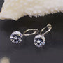Silver diamond charm hoop clip-on earrings with round crystal stones, front view on dark background