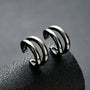 Polished silver double-band minimalist clip-on ear cuffs displayed at angle on dark textured surface