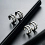 Silver double-band minimalist clip-on ear cuffs displayed at angle on black surface, showing sleek metallic design and modern style