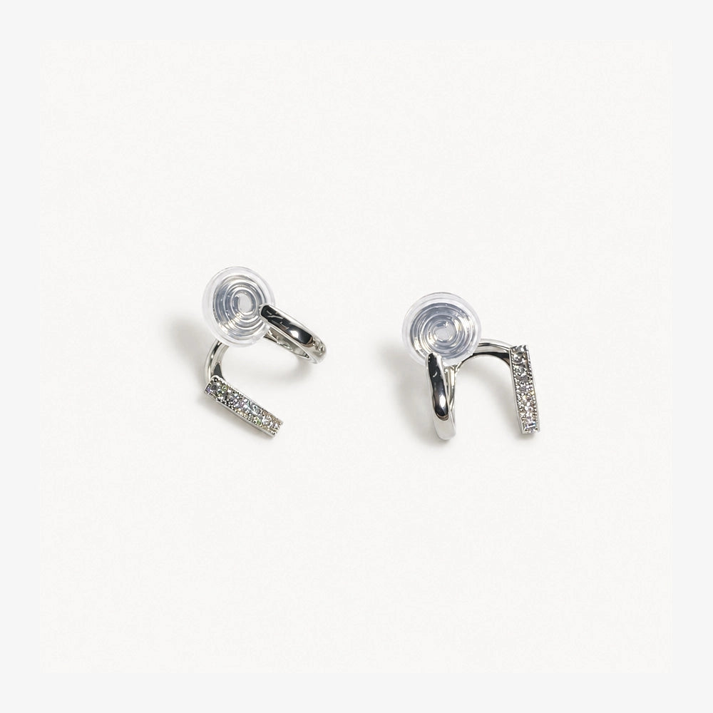 Silver double hoop clip on earrings displayed on white fabric with gold decorative accent below