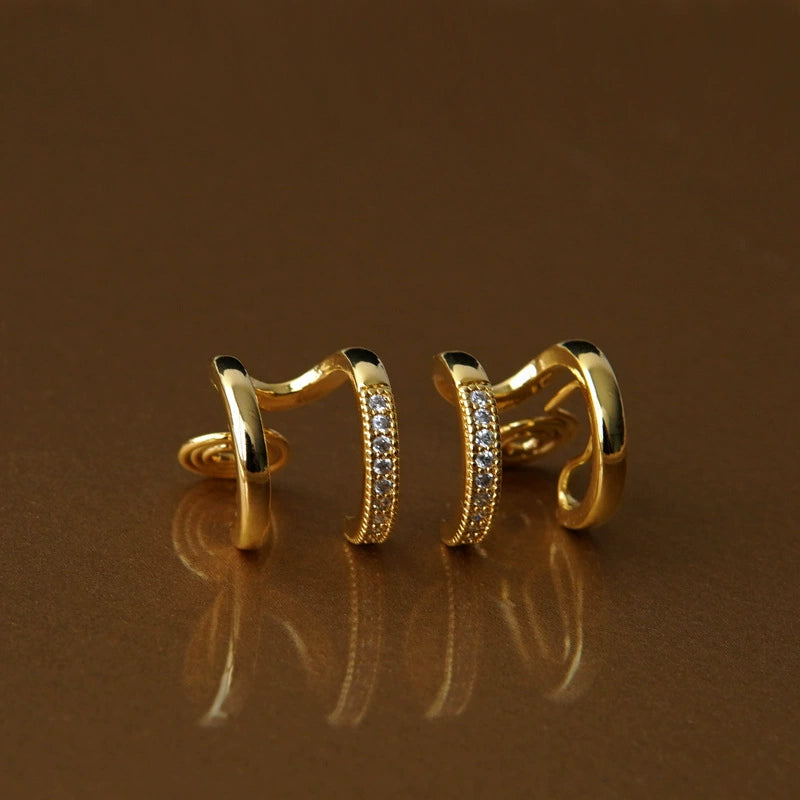Pair of gold clip on hoop earrings with a brown background