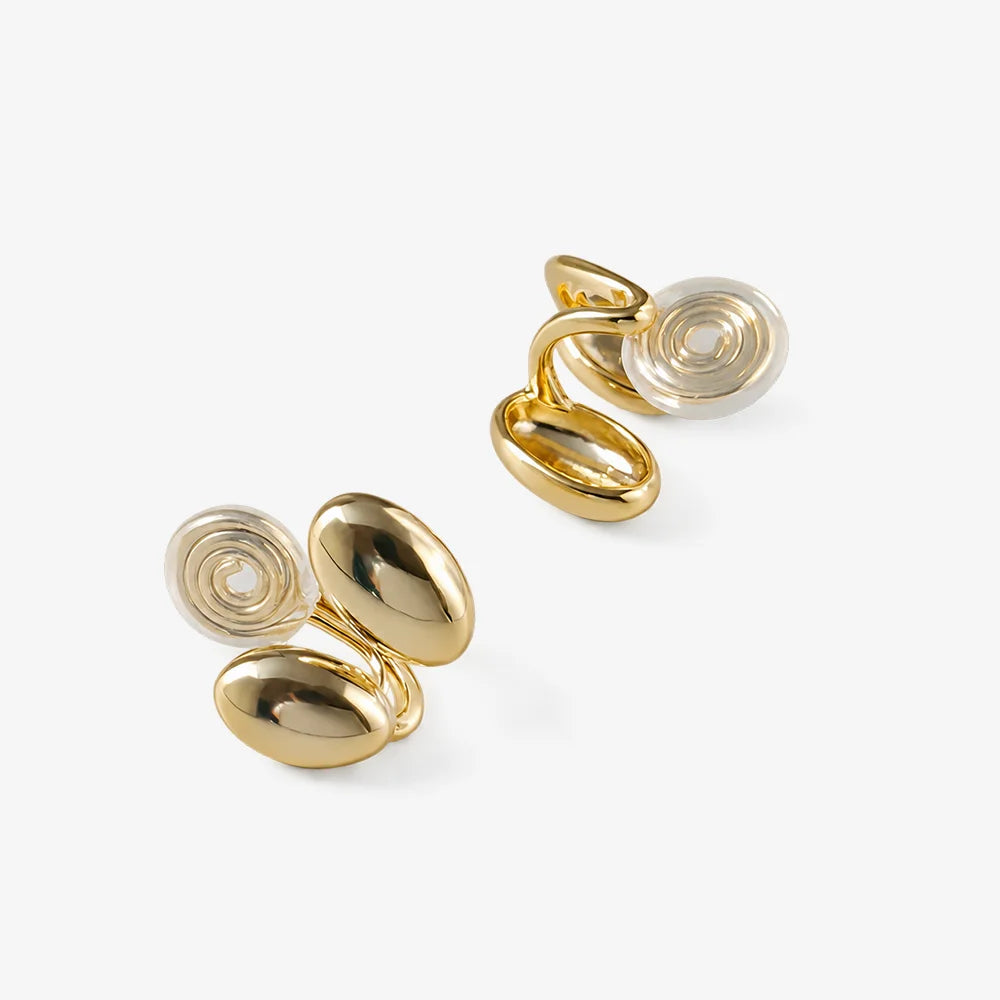Polished gold dual bean-shaped clip-on earrings displayed on white surface, angled view showing glossy finish and secure backing mechanisms
