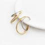 Two minimalist open hoop ear cuffs in polished yellow gold and silver, displayed on a clean white surface.