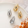 Ensemble de boucles d'oreilles pendantes minimalistes et imposantes, à clip, en argent et en or. Ces créoles en forme de haricot sont fabriquées dans un alliage poli et dotées d'un système de fermeture à clip à charnière pour une utilisation facile.