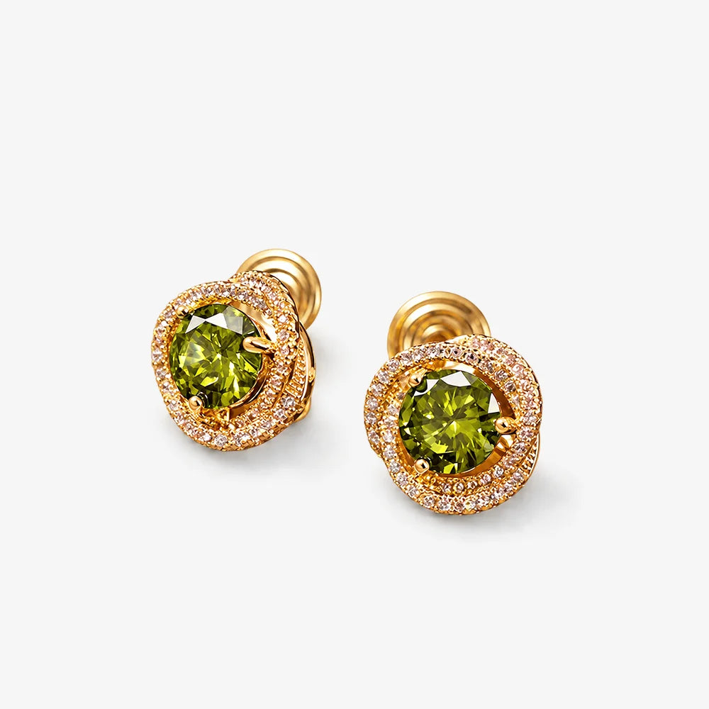 A pair of gold-plated stud earrings featuring a round green gemstone in the center, surrounded by a double halo of small clear pavé stones, set against a plain light gray background.