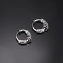 Silver Embrace clip-on hoop earrings with decorative twisted detail shown at angle on dark background