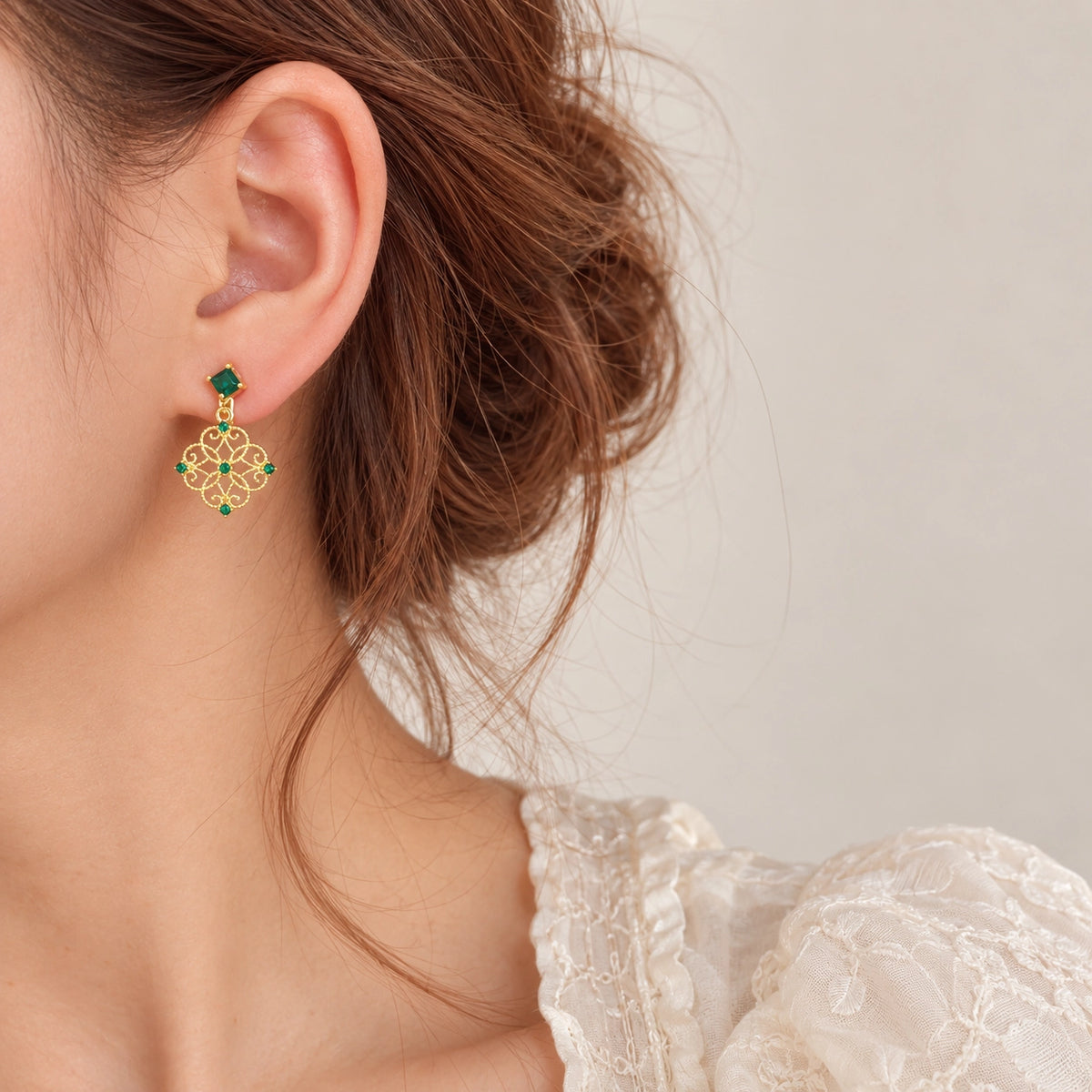 Emerald filigree dangle clip-on earrings side profile view on model with white background