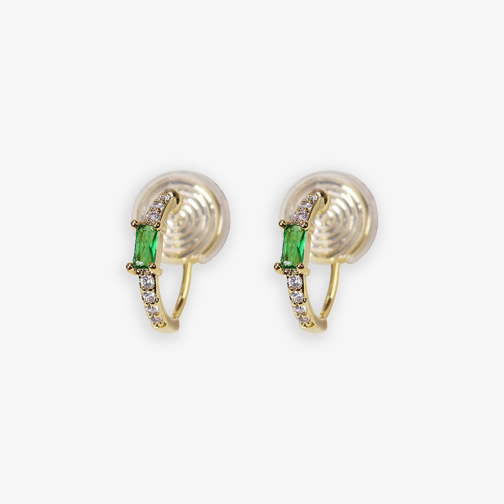 Experience the allure of classic jewels with these Emerald Huggie Hoop Clip-on Earrings. Each piece showcases a dazzling green zircon crystal, reminiscent of fine emeralds, complemented by a golden setting. 