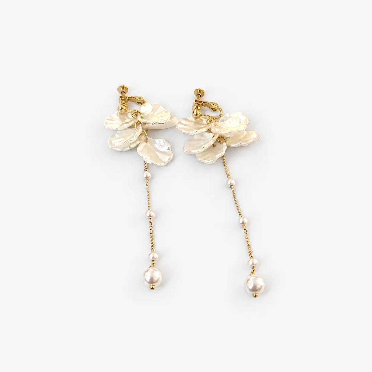 A pair of gold-toned dangle earrings featuring textured cream flower clusters, delicate chain links with small pearls, and larger dangling pearls, shown on a light gray background.