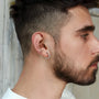 Silver geometric square clip-on earrings side profile view on model with beard wearing white shirt