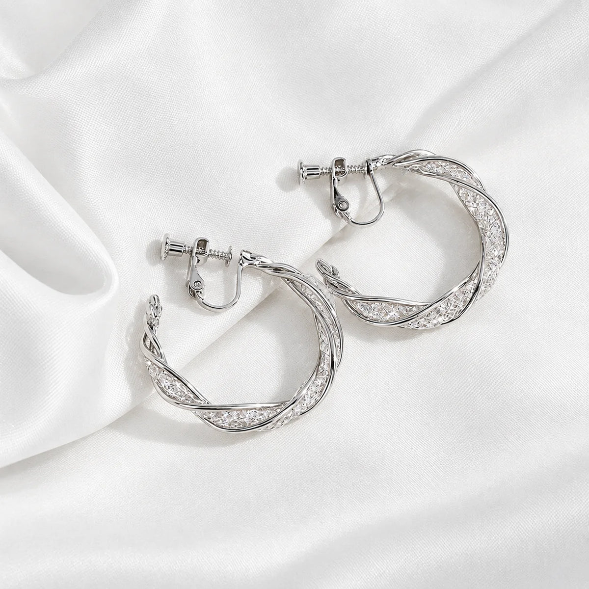 A pair of silver hoop earrings with a textured, twisted design and screwback closures, displayed on a clean white background.