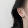 Glossy silver clip-on hoop earrings side view worn on ear against white background