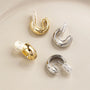 Glossy silver clip-on hoop earrings displayed on white background with gold and silver color variations