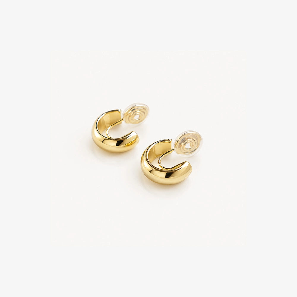Glossy gold clip-on hoop earrings displayed on white background, showing polished finish and curved design from above