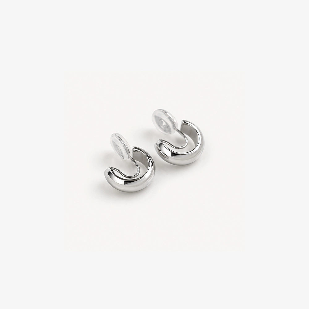 Glossy silver clip-on hoop earrings displayed at an angle on white background showing polished metallic finish and curved design