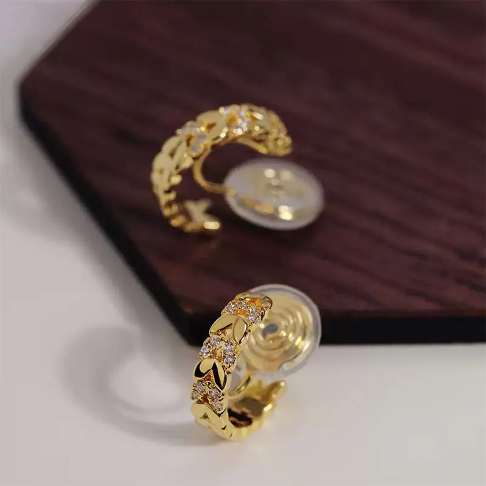 Gold chain zirconia clip-on hoop earrings displayed on burgundy box, showing detailed front angle view with cubic zirconia stones