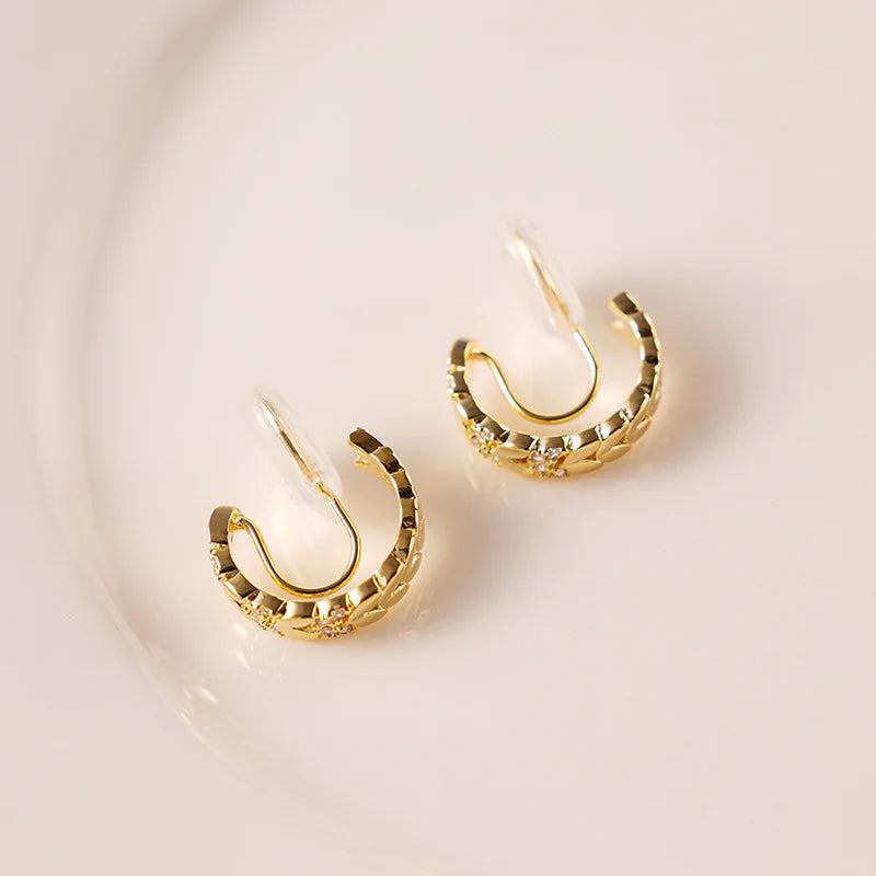 Gold chain zirconia clip-on hoop earrings displayed at an angle on a white background
