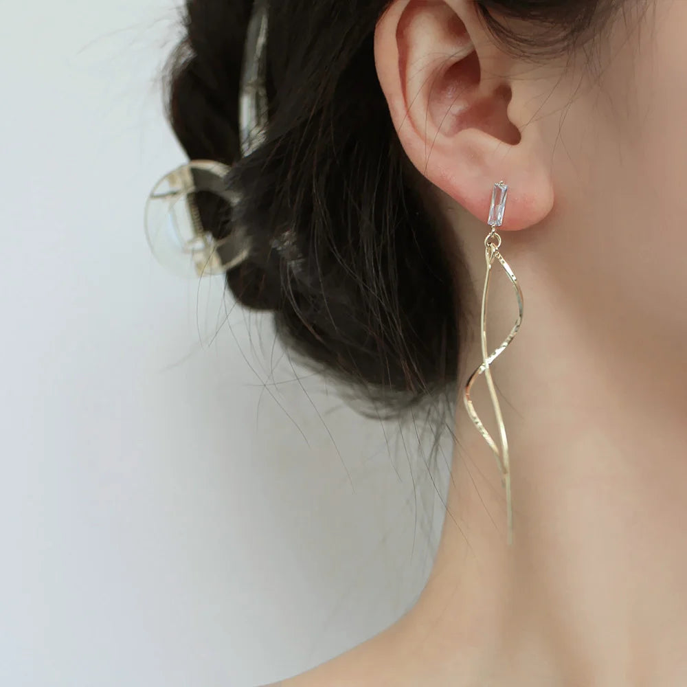Gold long tassel clip on earrings side view worn on ear with dark hair styled up