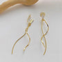 Gold long tassel clip-on earrings displayed on white background with wooden accent detail