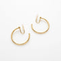 A pair of rotating yellow gold hoop earrings with u-type closures, shown on a clean white background.
