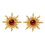 A pair of gold sunburst stud earrings with a polished round red cabochon gemstone in the center, set against a plain white background.