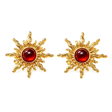 A pair of gold sunburst stud earrings with a polished round red cabochon gemstone in the center, set against a plain white background.