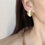 Gold square geometric clip on earrings side view worn on ear with dark hair
